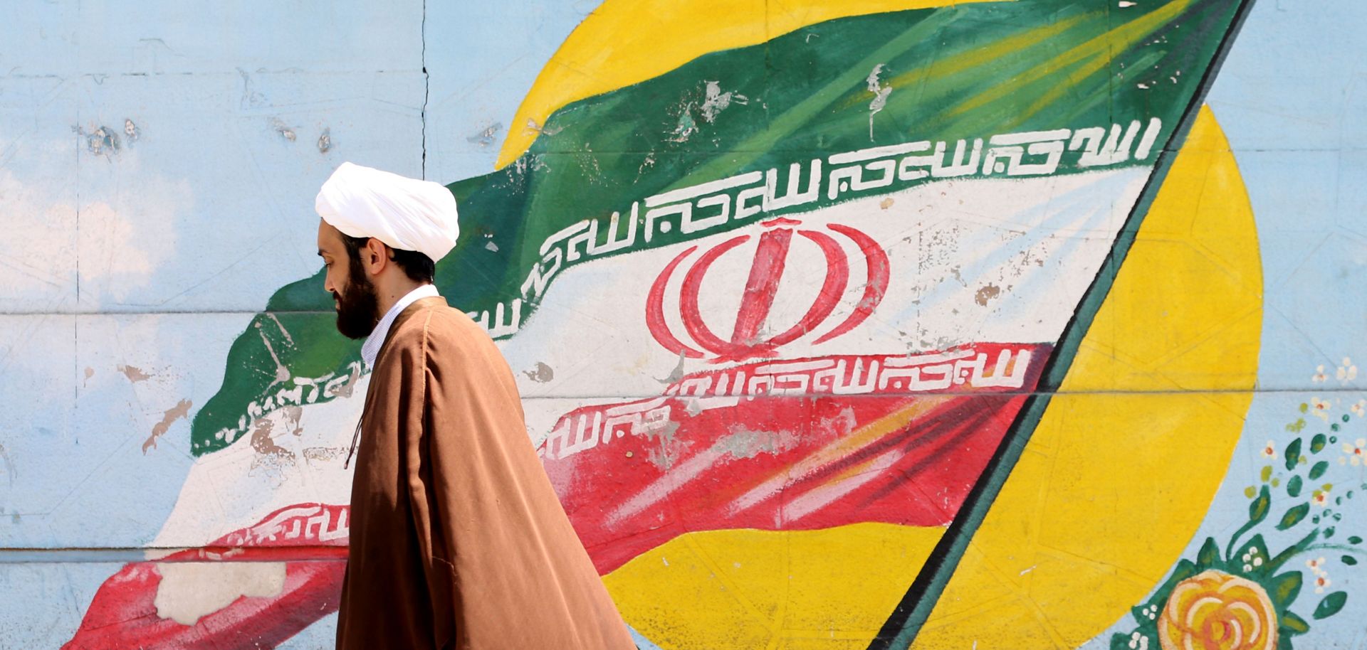 An Iranian cleric walks past a mural painting of the Iranian flag in Tehran on Aug. 27, 2019.