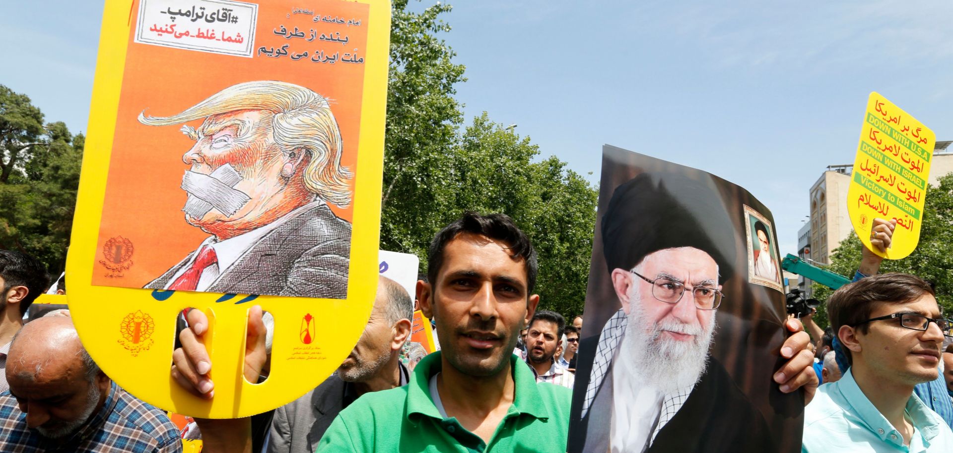 A protester holds a banner criticizing U.S. President Donald Trump and a portrait lauding Iranian Supreme Leader Ali Khamanei during an anti-U.S. demonstration in Tehran after Friday prayers on May 11. 