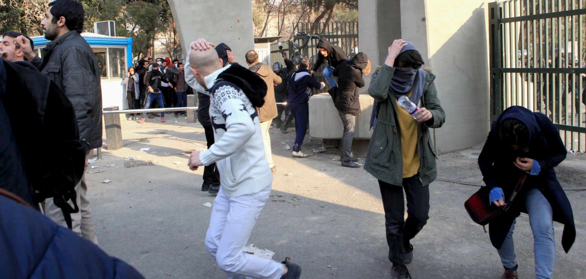 Students at the University of Tehran run for cover as tear gas is lobbed at demonstrators on Dec. 30, 2017.