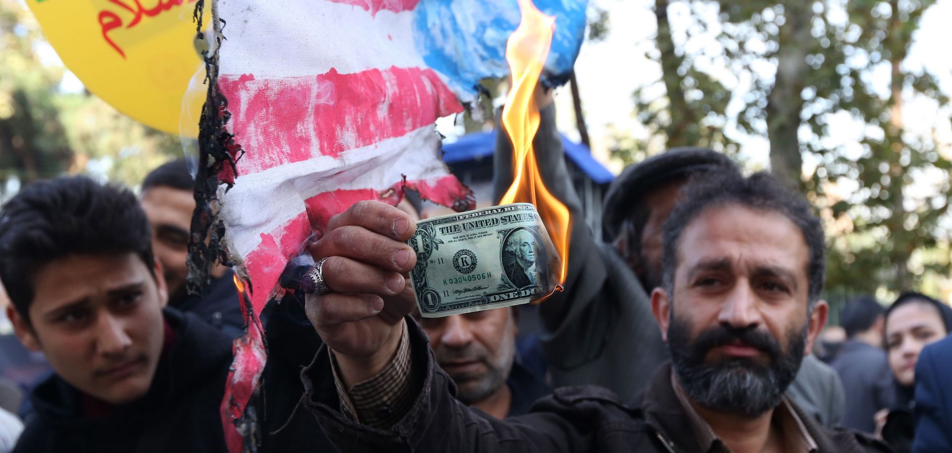 On the eve of renewed sanctions on Iran's oil sector, an Iranian protester burns a U.S. dollar.