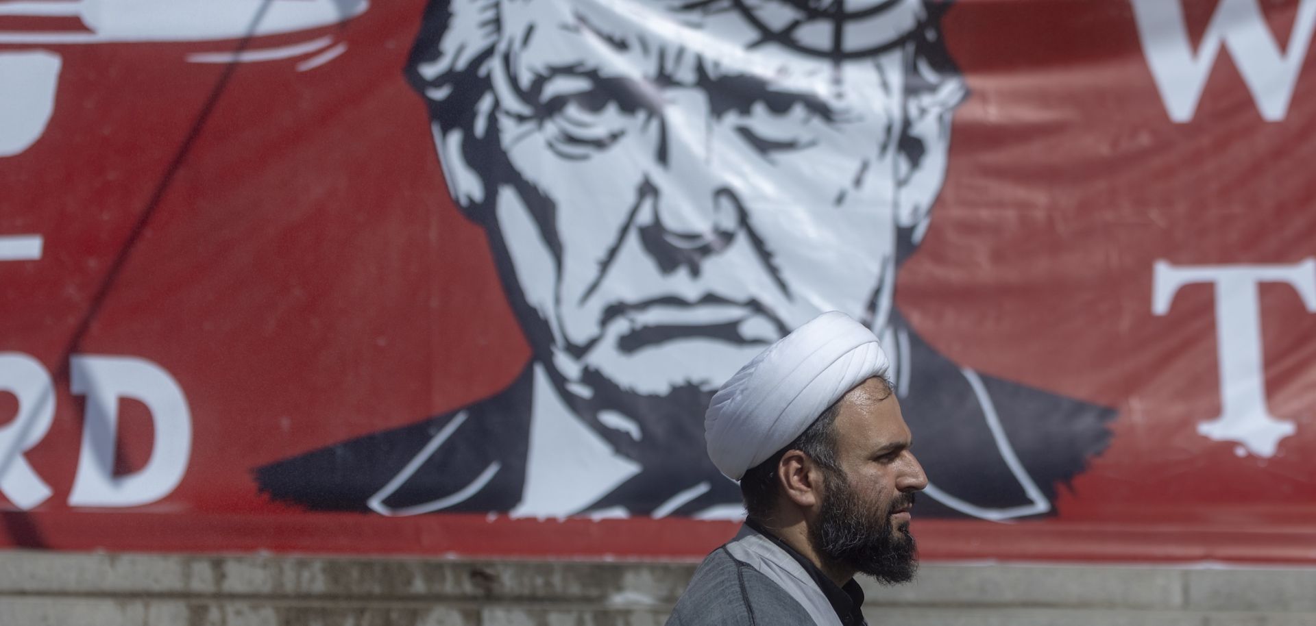 People pass a large banner depicting U.S. President Donald Trump with a target on his head, during funeral ceremonies for Iran's slain Supreme Leader, Ayatollah Ali Khamenei, at the Grand Mosalla on July 5 in Tehran, Iran. 