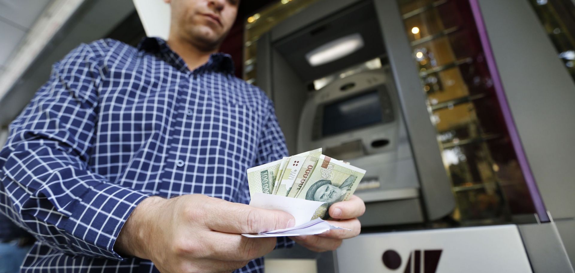 A man withdraws Iranian Rials from an ATM