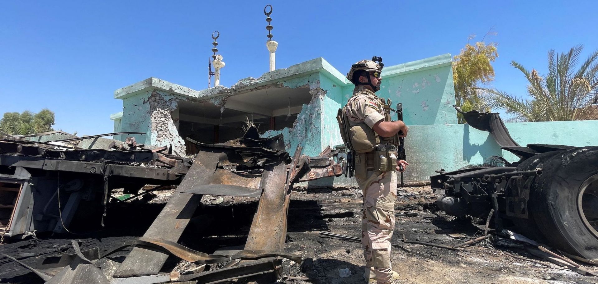 A member of the Iraqi security forces stands by a destroyed vehicle on July 8, 2021, after rockets landed on the Ain al-Asad airbase in Iraq’s western Anbar province, which hosts U.S. troops. 