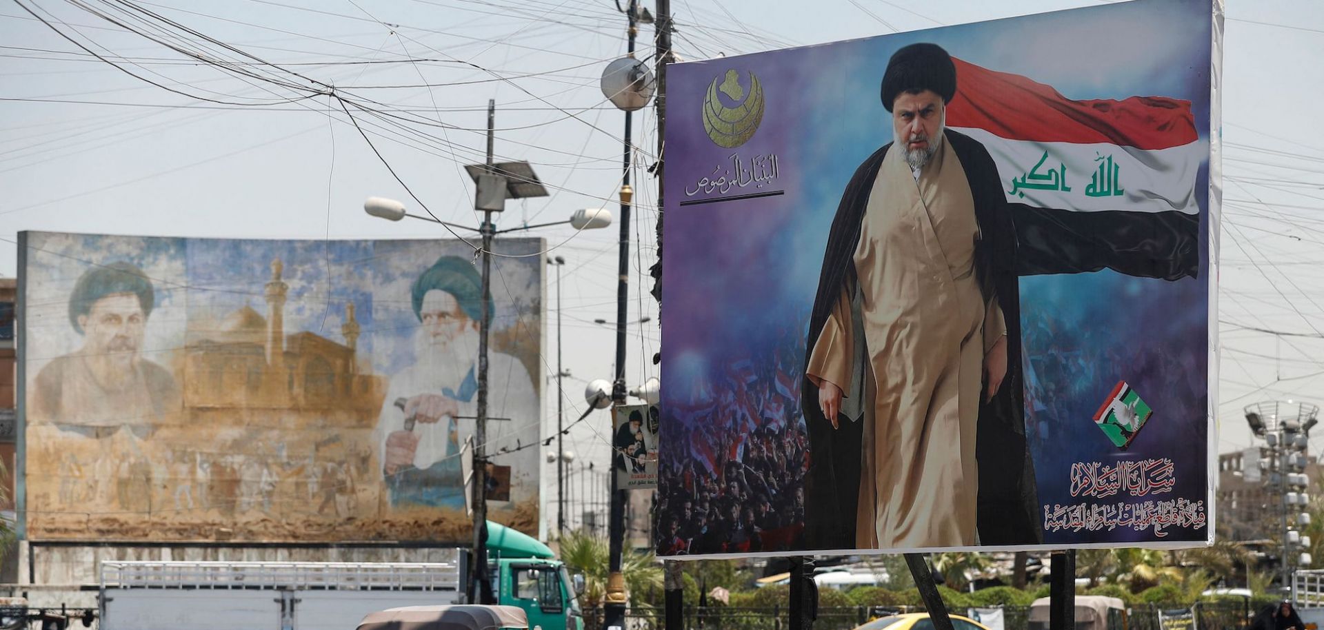 A tuk-tuk car drives past a large poster of Shiite cleric Moqtada al-Sadr, in al-Sadr City, Iraq, on July 15, 2021. 