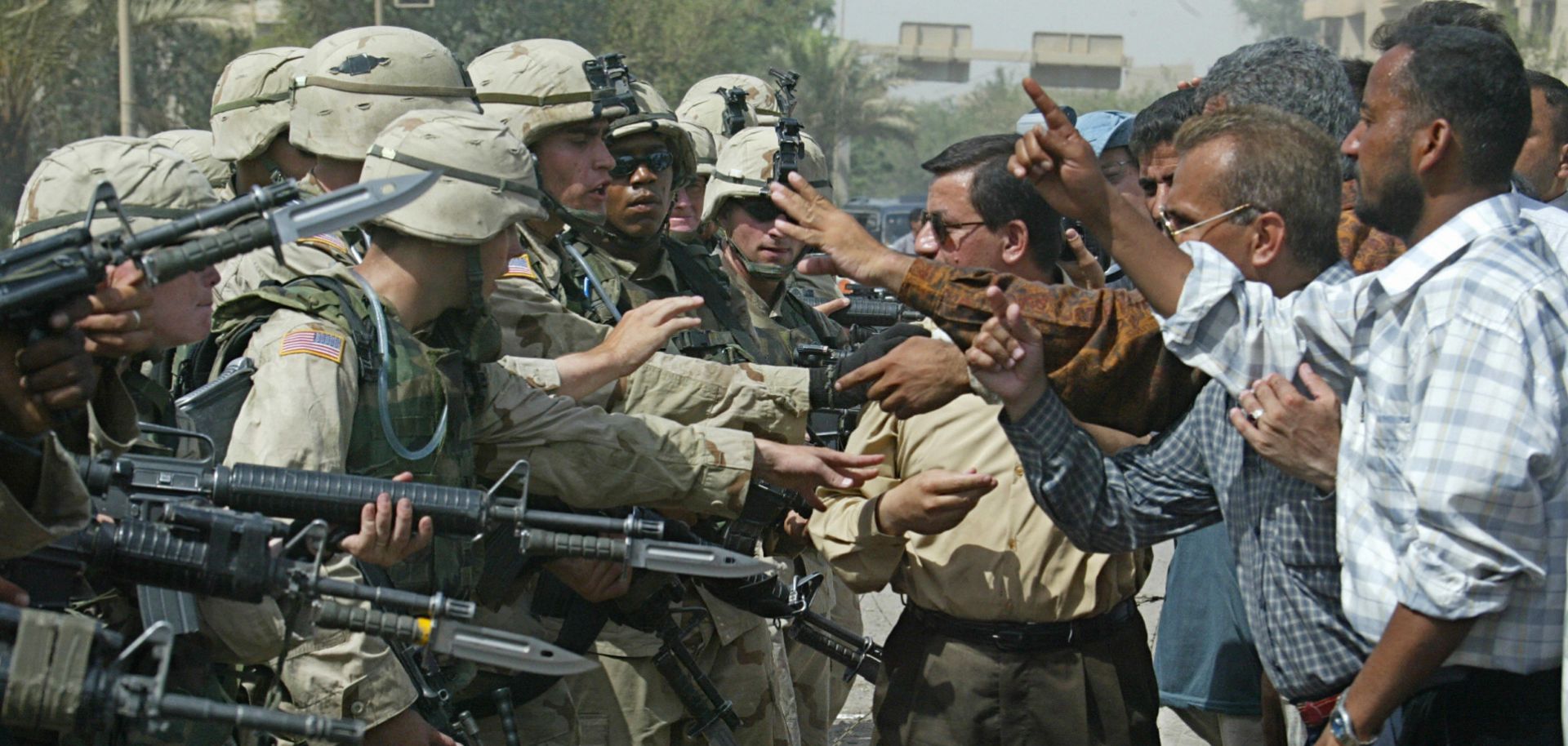 U.S. troops guard the entrance of the U.S. administration's offices in Baghdad as ex-Iraqi army personnel stage a protest, June 18, 2003. 
