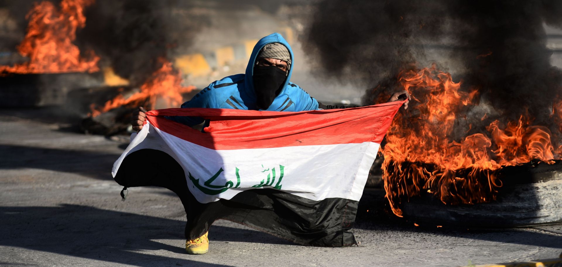 An Iraqi demonstrator poses with the national flag as angry protesters blocked roads in the central city of Najaf on Jan. 5, 2020, to oppose the possibility that Iraq would become a battleground between the United States and Iran.