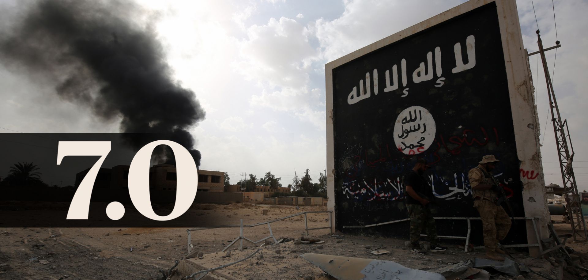 Iraqi fighters enter the city of Qaim on Nov. 3 near a wall bearing an image of the Islamic State flag.