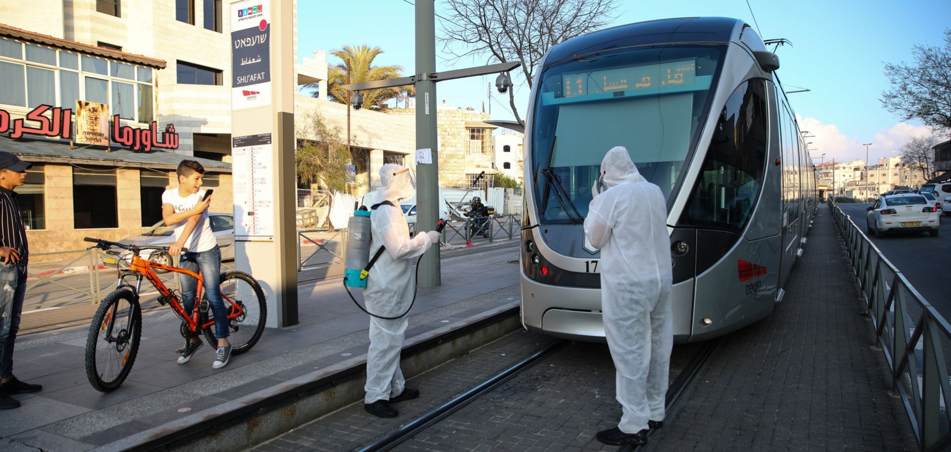 Officials in hazmat suits disinfect the outside a tram as a precaution against the coronavirus outbreak in Jerusalem, Israel on March 16, 2020.