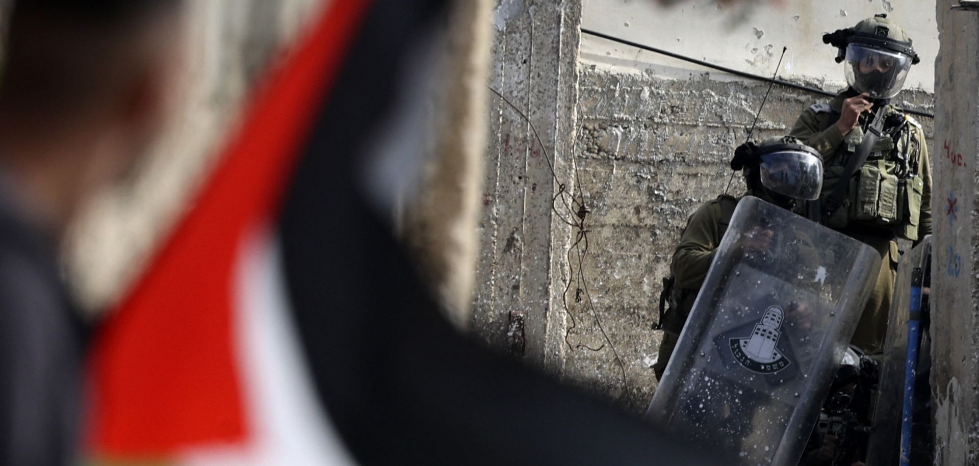 A Palestinian demonstrator waves a flag during confrontations with Israeli troops Jan. 6, 2023, in the West Bank village of Kfar Qaddum, near the Jewish settlement of Kedumim.