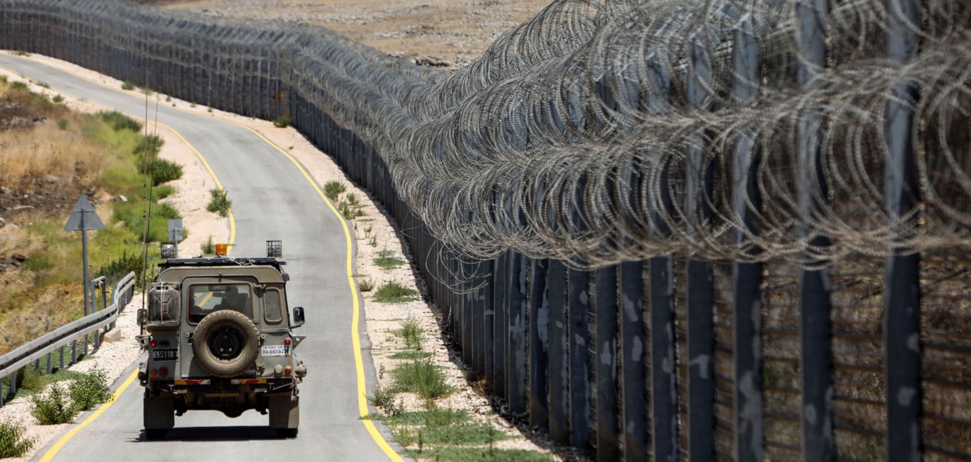 An Israeli army vehicle drives on the road along the border fence that separates the Israeli-annexed Golan Heights and Syria on July 19, 2017.