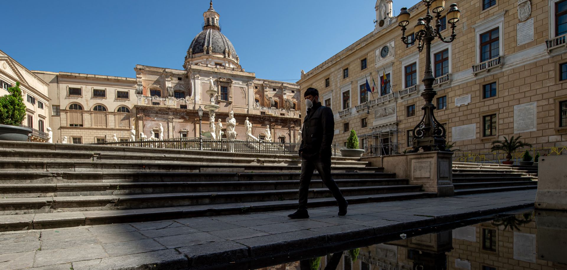 A man wearing a face mask walks in Pretoria square in Palermo, Italy, on March 11, 2020.