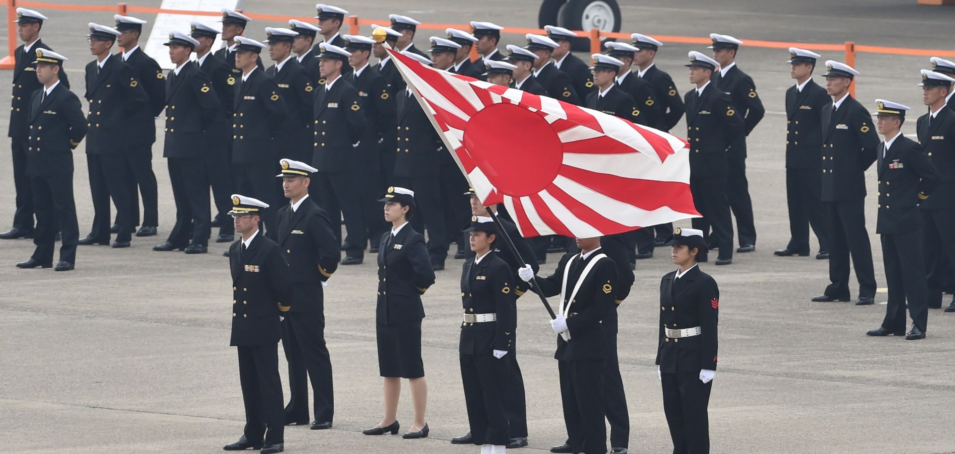 Japanese navy servicemen in Omitama stand with their flag on a runway in anticipation of an upcoming ceremony. 