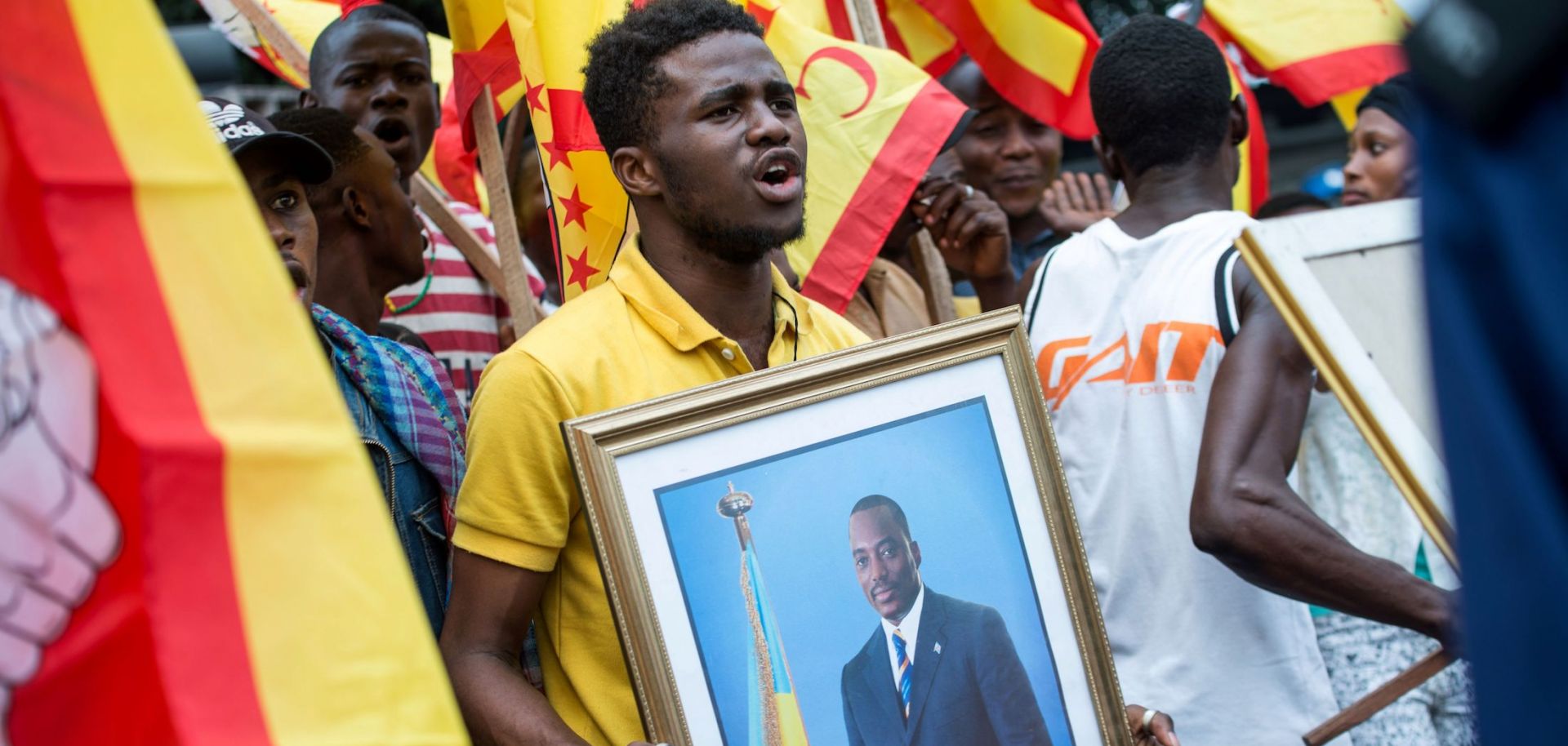 In this photo, a supporter of Congolese President Joseph Kabila stands with other people gathered outside parliament in the capital of Kinshasa, where Kabila was speaking on July 19, 2018.