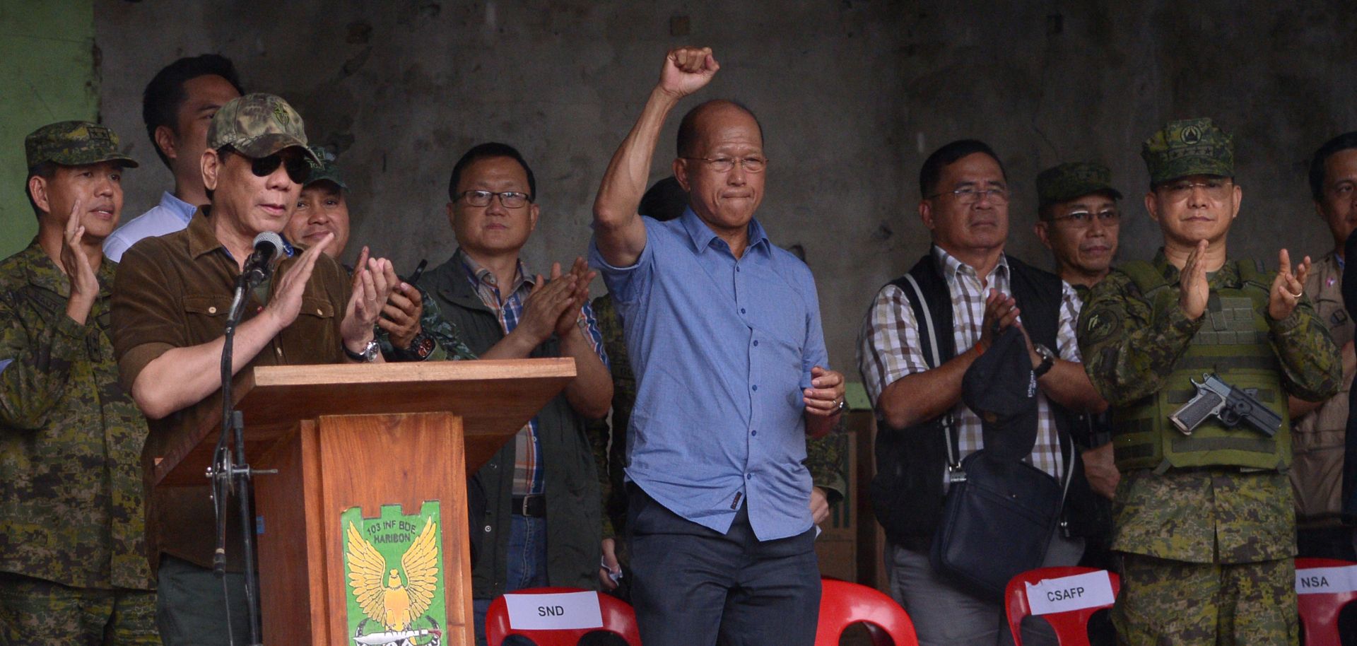 Philippine Defense Minister Delfin Lorenzana (center) raises his fist in victory as President Rodrigo Duterte declares the end of the siege of Marawi City on Oct. 17.