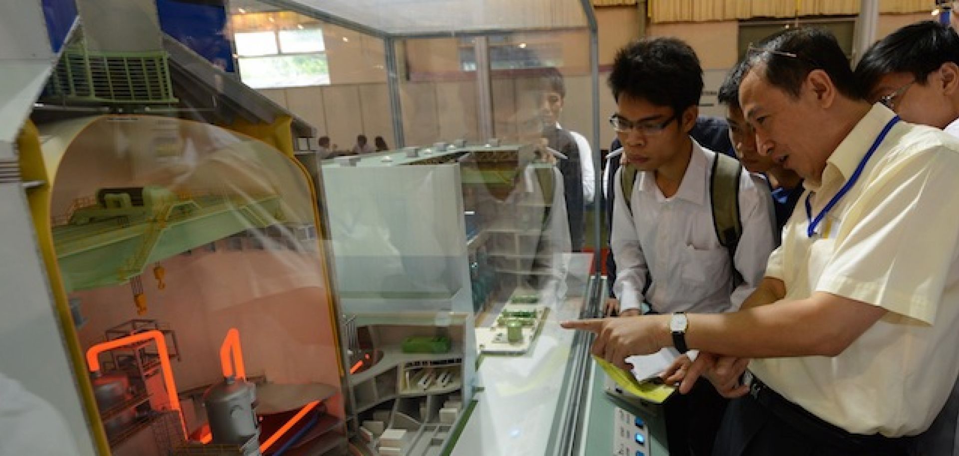 An expert (R) explains a nuclear reactor to students in Hanoi.