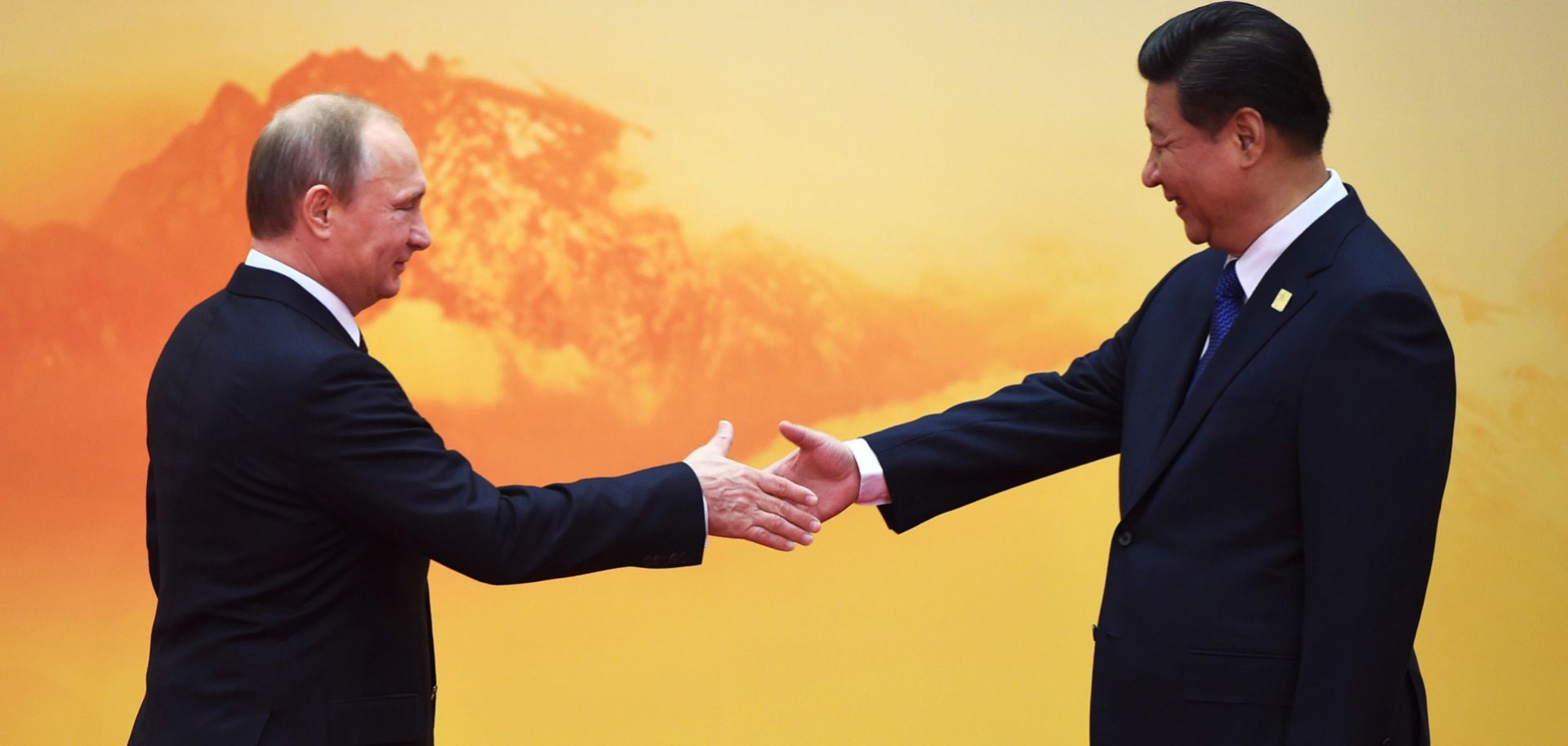 Russian President Vladimir Putin (L) shakes hands with Chinese President Xi Jinping.