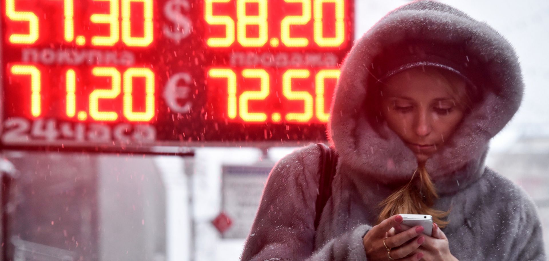 A woman in Moscow walks past a sign showing the Russian ruble's value compared the the U.S. dollar and euro.
