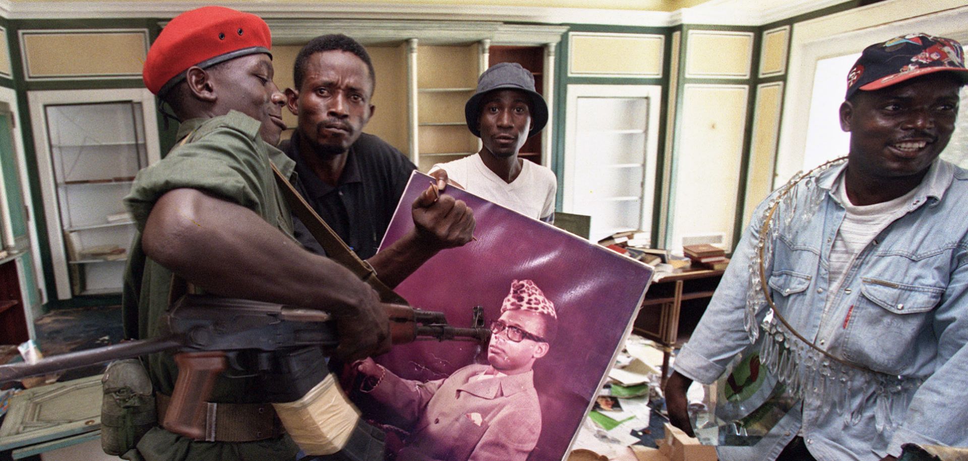 A Congolese rebel alliance soldier surrounded by looters in Kinshasa prods a photograph of ousted Zairean President Mobutu Sese Seko in 1997. African populations are demanding more from their leaders, and not all leaders are prepared to give it.