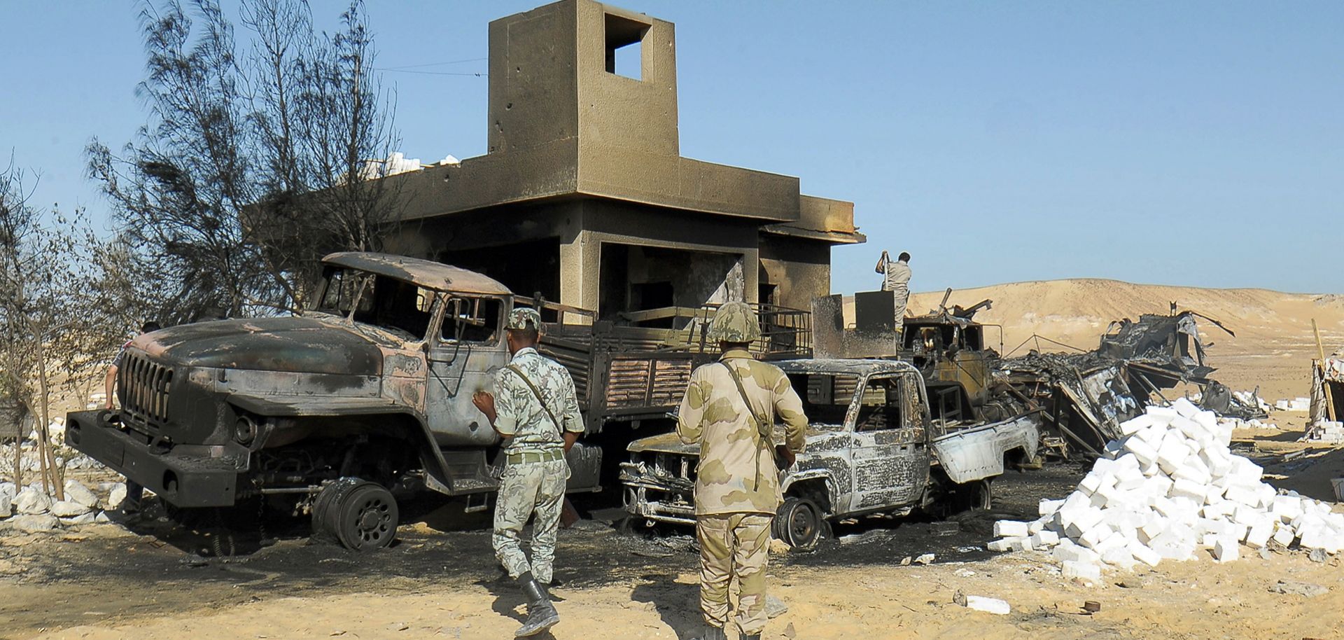 Egyptian soldiers search the site of an attack by militants that killed 21 border guards in al-Wadi al-Gadid