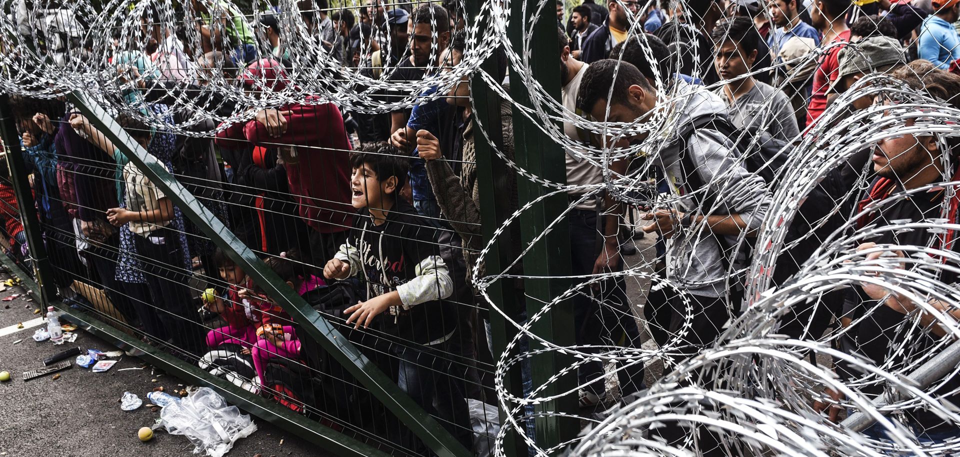 Refugees stand behind a fence at the Hungarian border with Serbia 