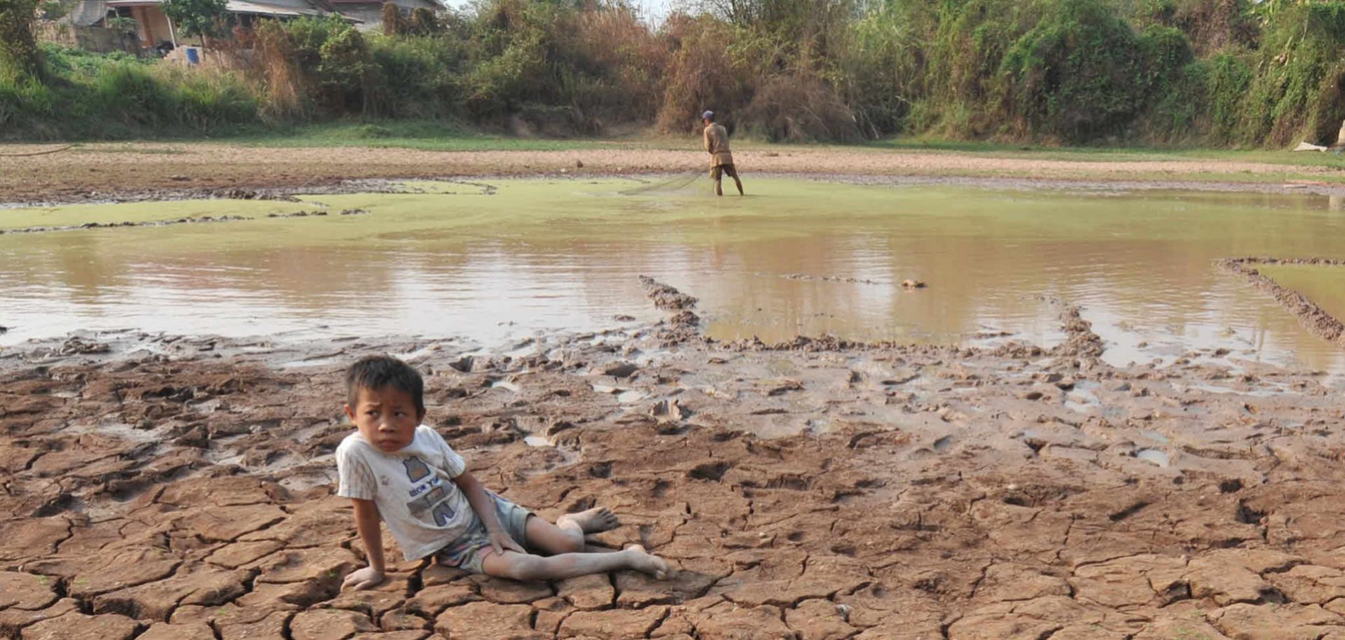 A son waits while his father fishes in their family's rice field outside the Laotian capital Vientiane, near the Mekong River, on March 27, 2010. Severe droughts have depleted the river waters to historic lows, leaving rice fields dry and unproductive.