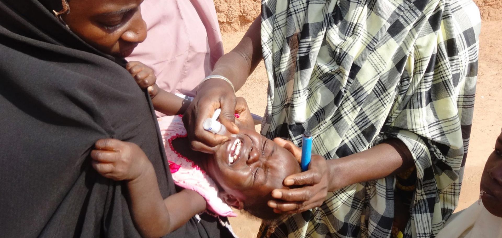 A health care worker administers an oral dose of polio vaccine to a child in northern Nigeria.