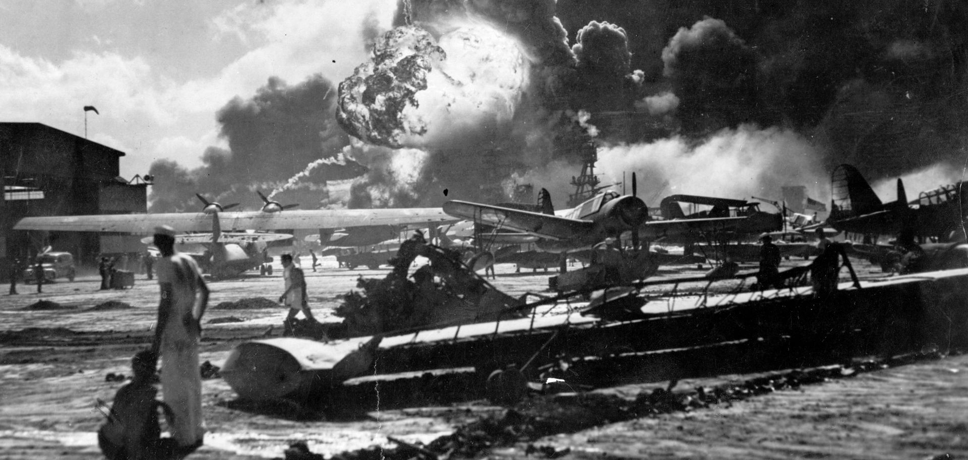 Sailors stand amid wreckage watching as the USS Shaw explodes on Dec. 7, 1941, at the Naval Air Station, Ford Island, Pearl Harbor.