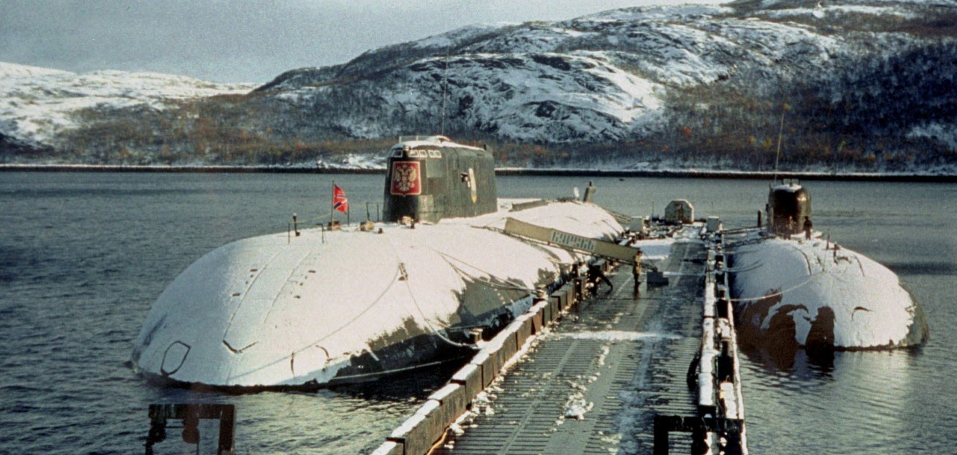 The ill-fated Kursk submarine (L) sits in port in the winter of 2000.