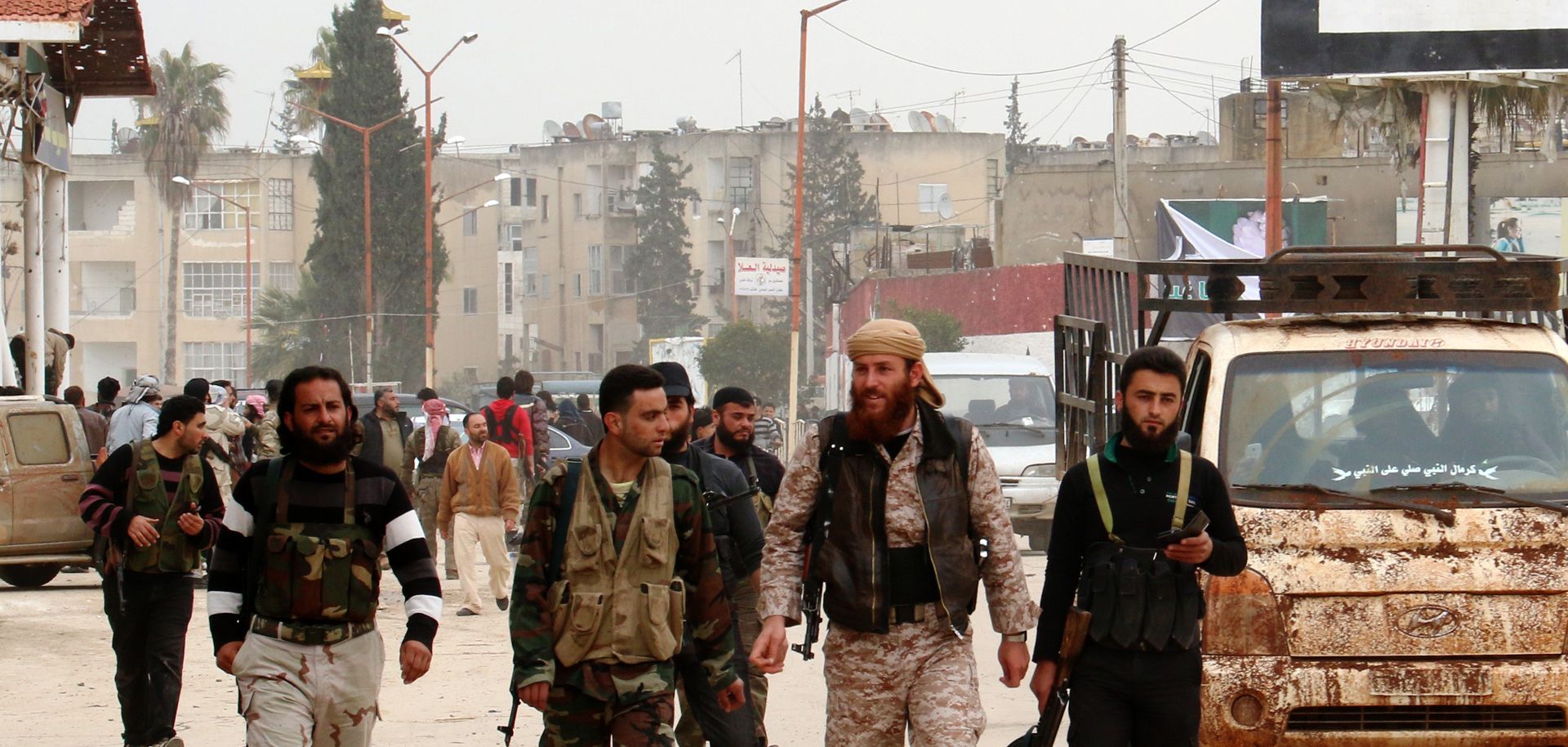 Fighters from a coalition of Islamist forces walk through the Syrian city of Idlib on March 29.