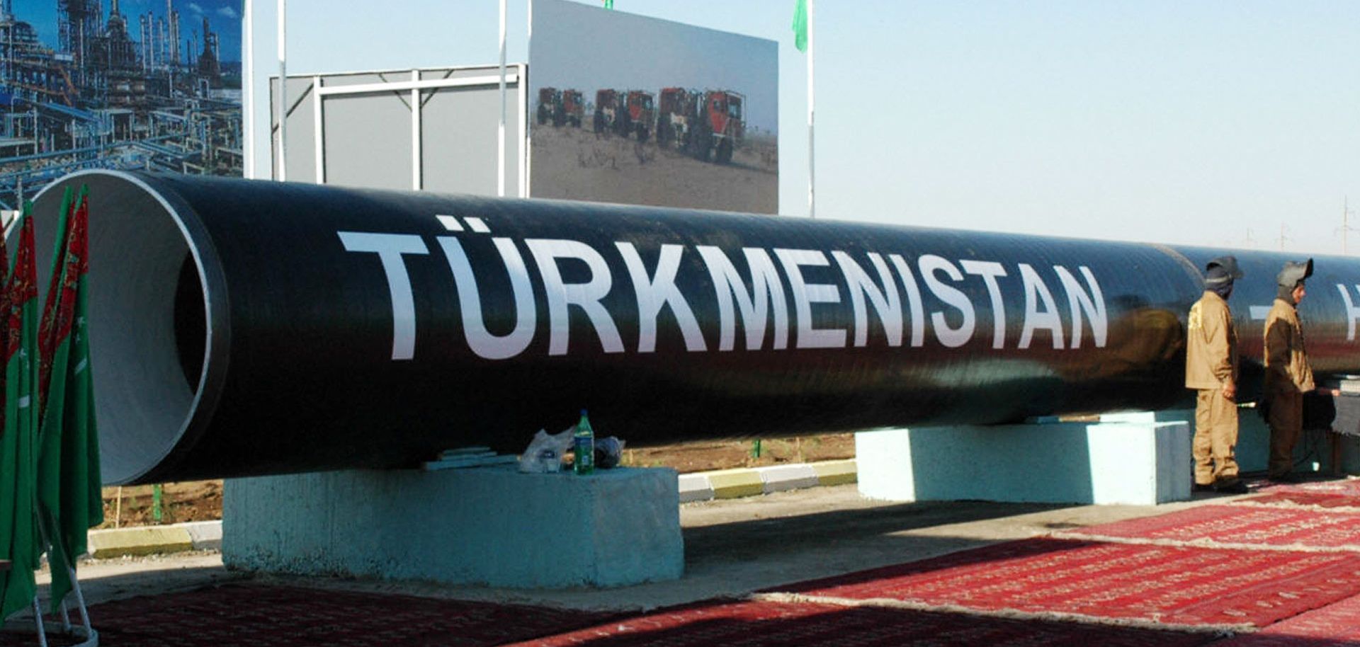 Two workmen stand next to the symbolic first piece of a natural gas pipeline to China outside of Turkmenabat in 2007.