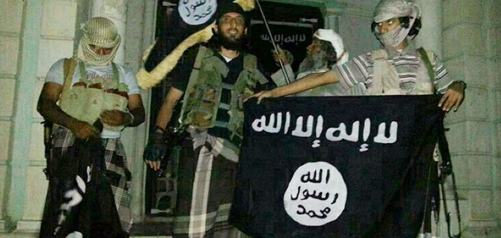A picture taken with a mobile phone early on May 24, 2014 shows Al-Qaeda militants posing with Al-Qaeda flags in front of a museum in Seiyun, second Yemeni city of Hadramawt province, after launching a massive pre-dawn assault that killed at least 15 soldiers and police. The assault in Hadramawt, a jihadist stronghold that has seen large-scale attacks on the army in the past, came as troops pressed a month-old ground offensive against Al-Qaeda in Abyan and Shabwa provinces to the west. AFP PHOTO / STR (Phot