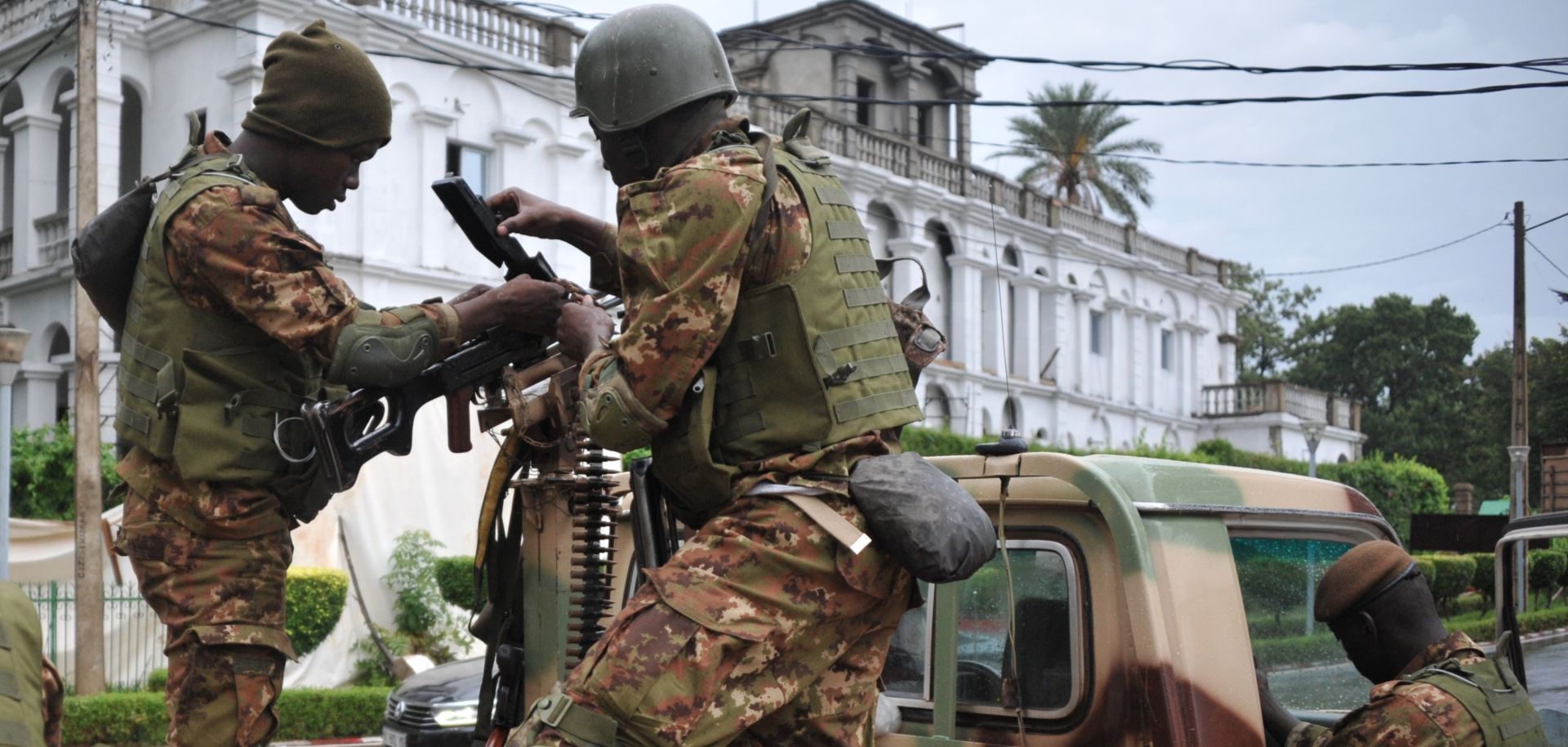 Malian soldiers outside the presidential palace in Bamako service the weapon on a military vehicle.