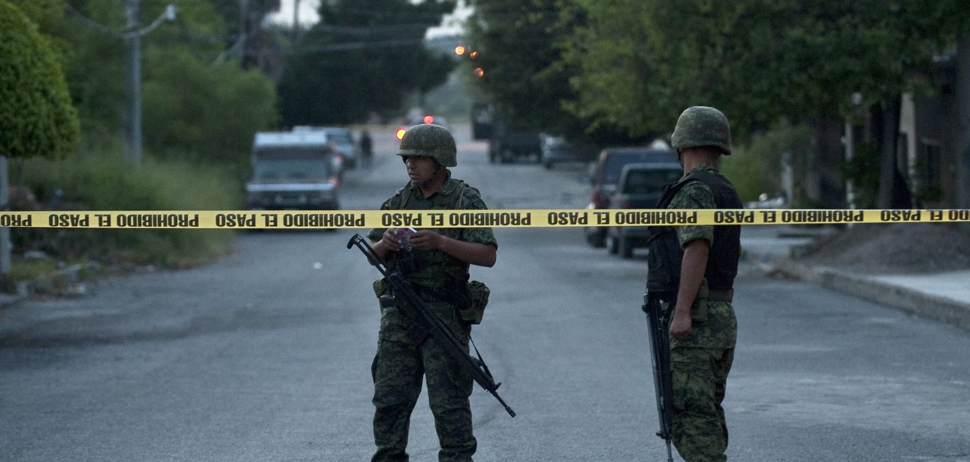 Mexican soldiers stand near the scene of a car bombing.