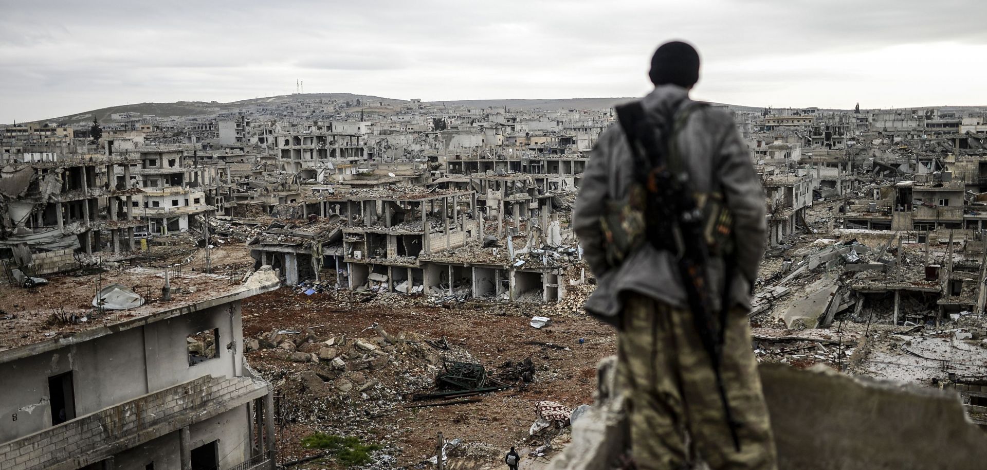 A man stands on top of a building overlooking the destryoed town of Kobane, Syria.