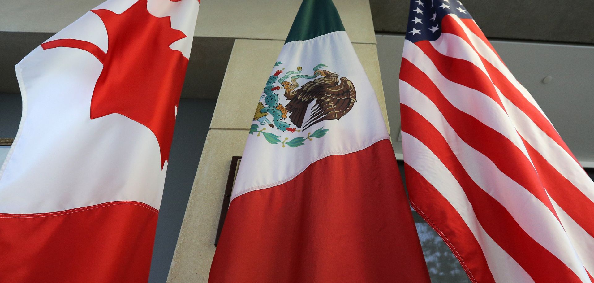 The flags of Canada, Mexico and the United States hang outside the negotiating room during the third round of talks in September to revise the North American Free Trade Agreement.