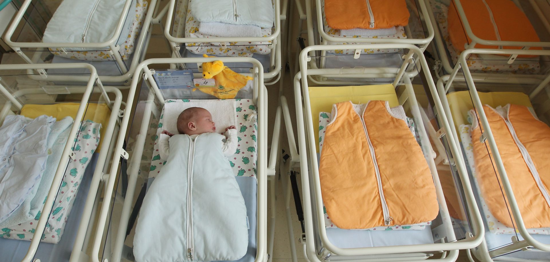  A 4-day-old newborn baby, who has been placed among empty baby beds in the maternity ward of a hospital.