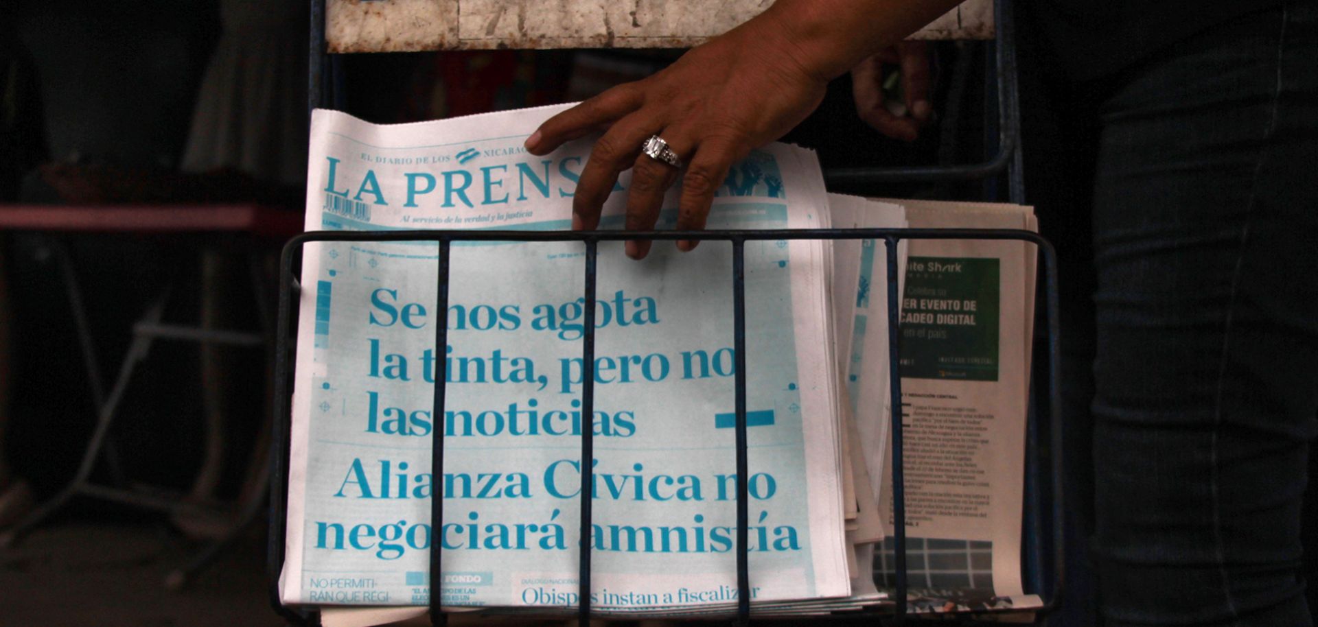 A passerby picks up a copy of Nicaragua's La Prensa in Managua on March 25, 2019. The newspaper printed its cover in cyan, instead of black, with the headline, 'We are running out of ink, but not of news. The Civic Alliance will not negotiate an amnesty.'