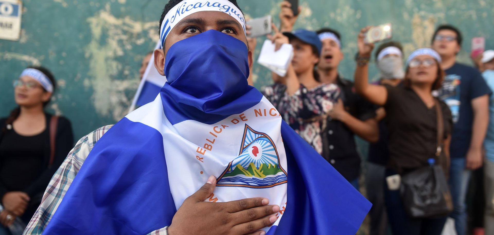 In this photograph, demonstrators sing the Nicaraguan national anthem in front of a police station during a protest against President Daniel Ortega's government in Managua on April 25.