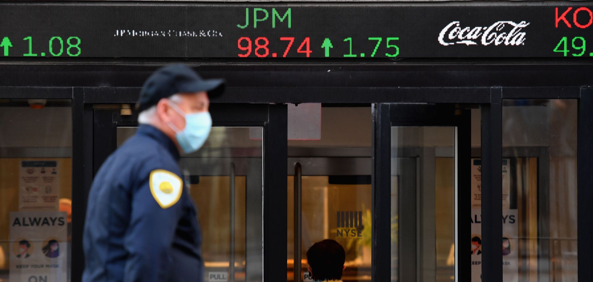 People wearing masks walk by the New York Stock Exchange (NYSE) in lower Manhattan on Oct. 5, 2020, in New York City.