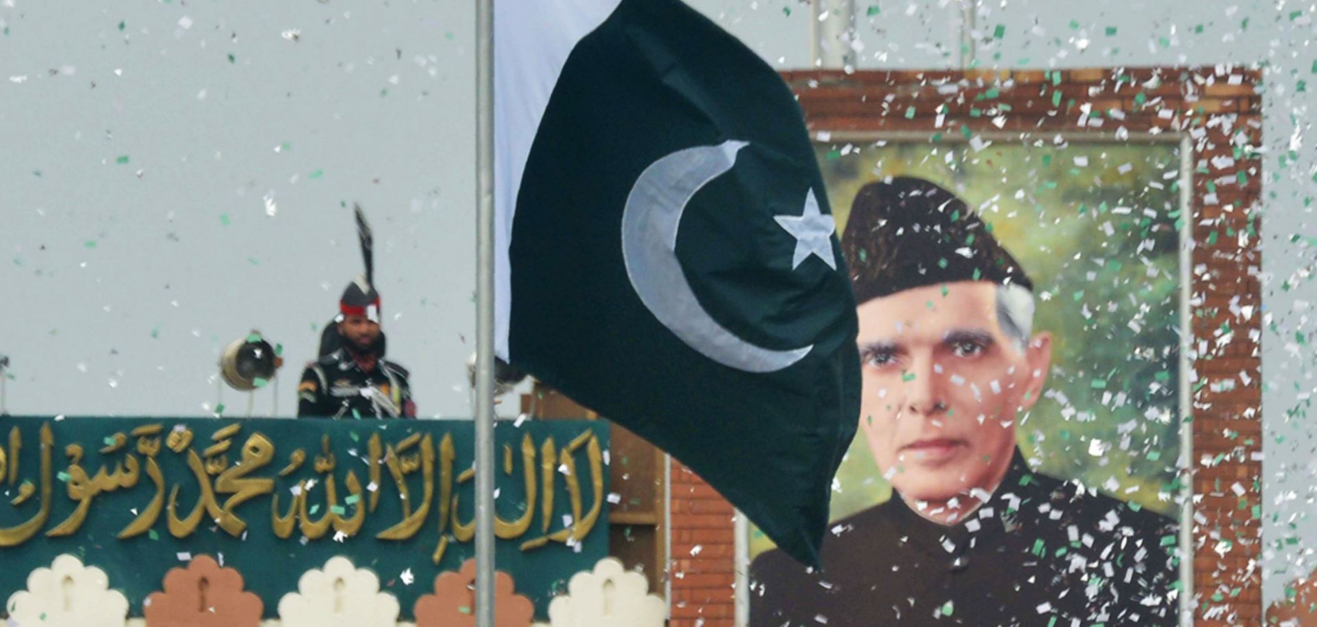 A Pakistani ranger unfurls the Pakistani national flag next to a banner with face of Muhammad Ali Jinnah, the founder of Pakistan, on the anniversary of the country's independence. 