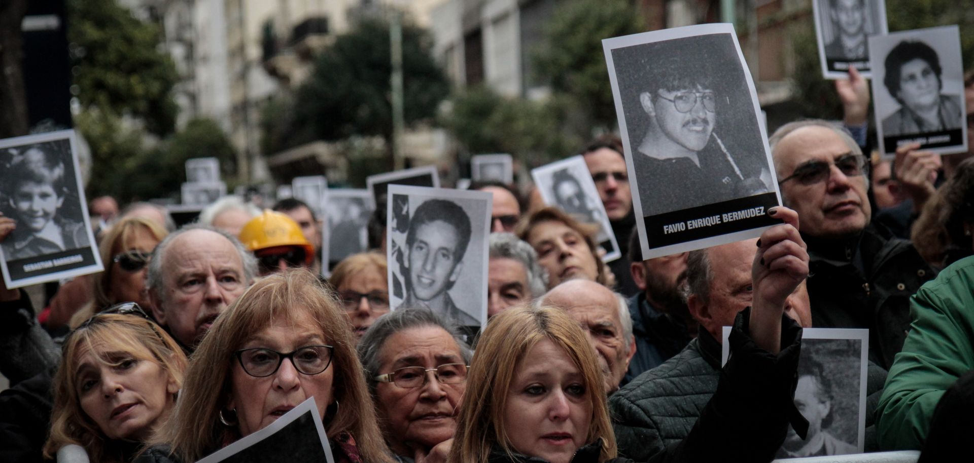 People hold up pictures of victims at a commemoration ceremony 25 years after the terrorist attack on the Jewish community AMIA.