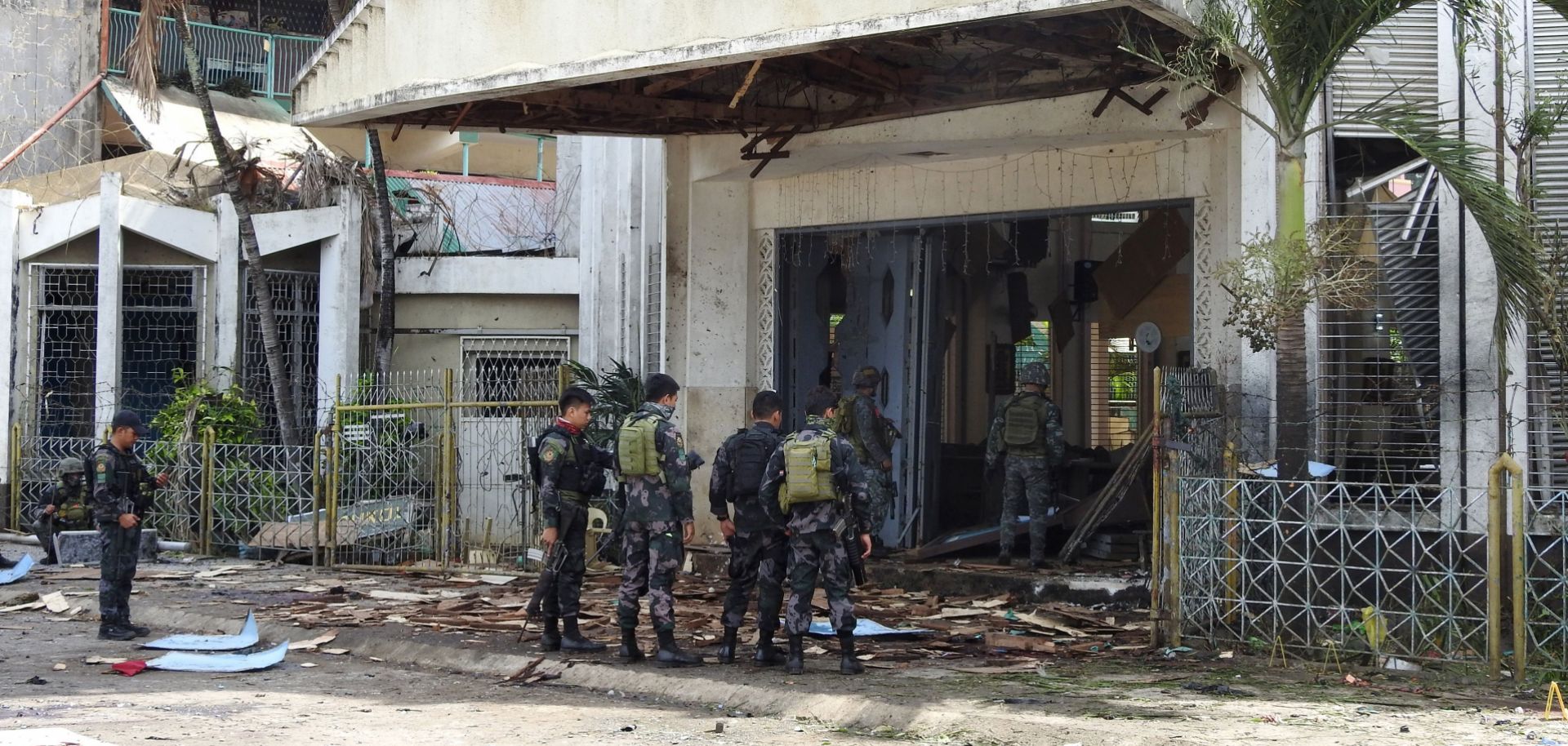 Police officers and soldiers stand outside a Catholic church in Jolo, Philippines, on Jan. 27, 2019, the day after two suicide bombings killed 20 people.