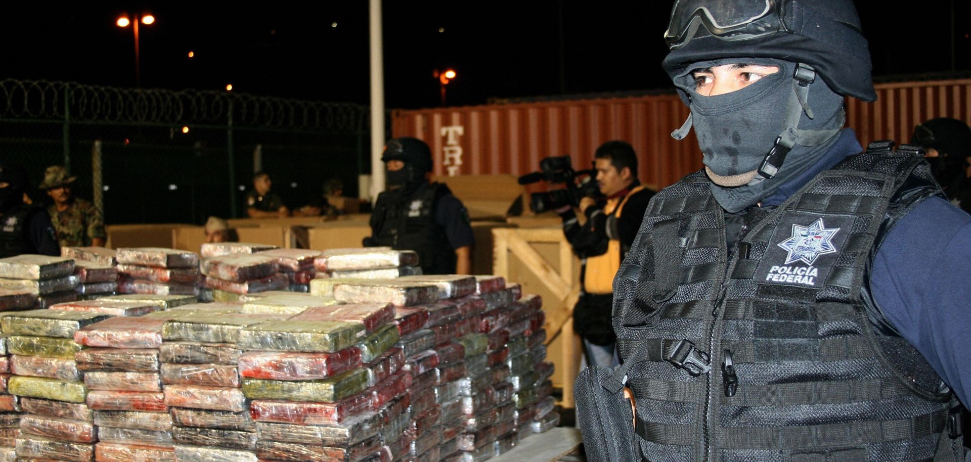 Police guard stacks of seized cocaine.