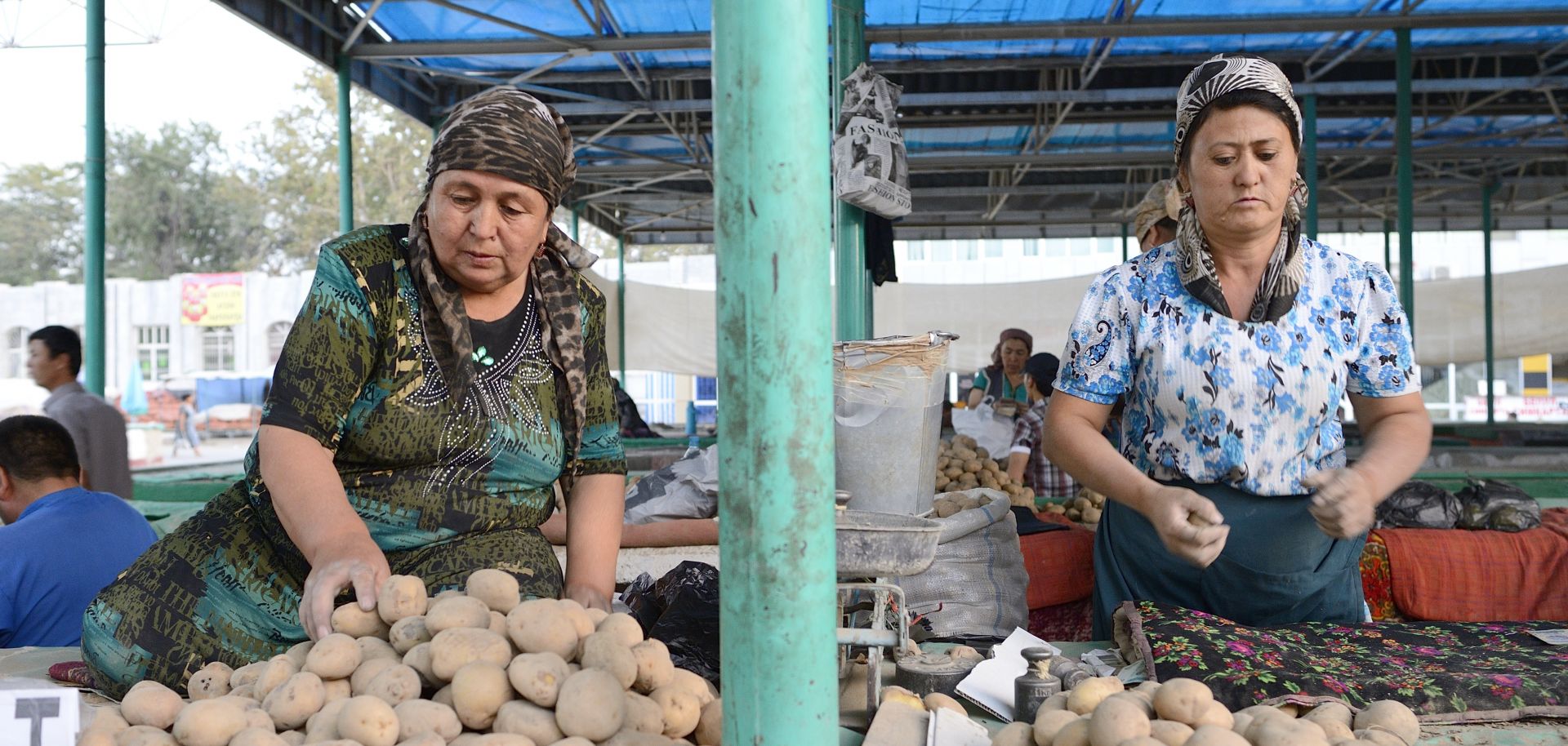 Women kneel in a potato market in the Fergana Valley.