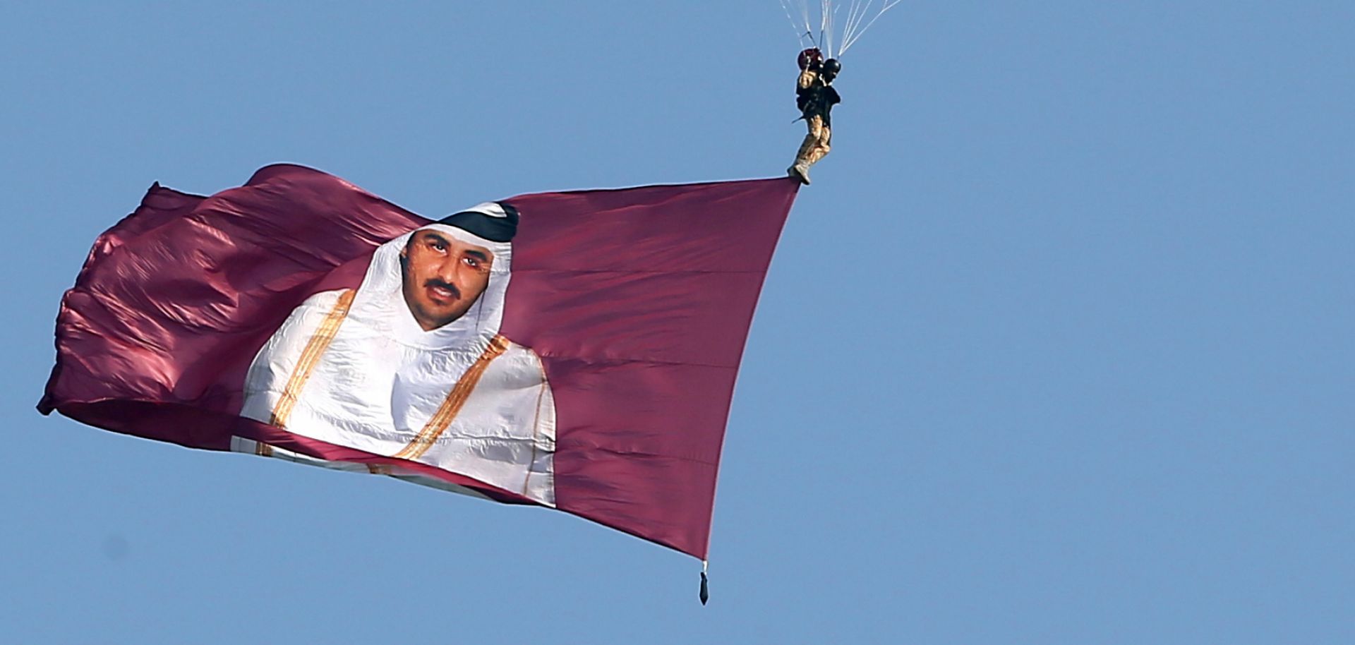 A paraglider displays a flag depicting Qatar's leader, Sheikh Tamim bin Hamad al-Thani.