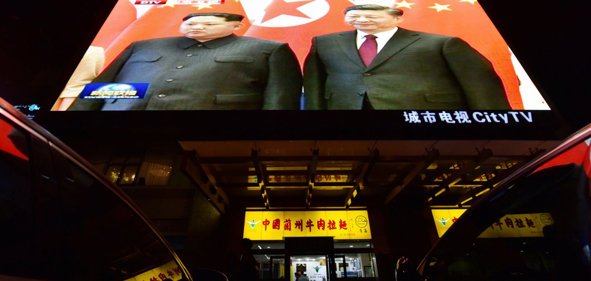 News footage of North Korean leader Kim Jong Un, left, and Chinese President Xi Jinping is shown above a Beijing restaurant on March 28, 2018.