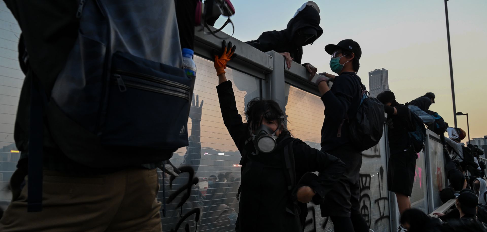This photo shows pro-democracy protesters in Hong Kong fleeing from police by climbing over highway dividers during a mass rally on Dec. 1, 2019.