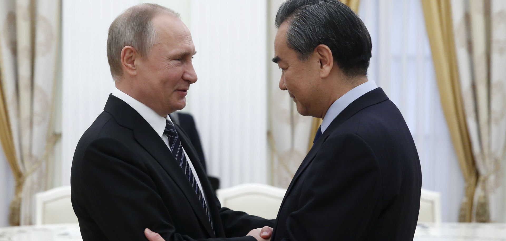 Russian President Vladimir Putin, pictured here with Chinese Foreign Minister Wang Yi, has reason to collaborate with Beijing in Kyrgyzstan.