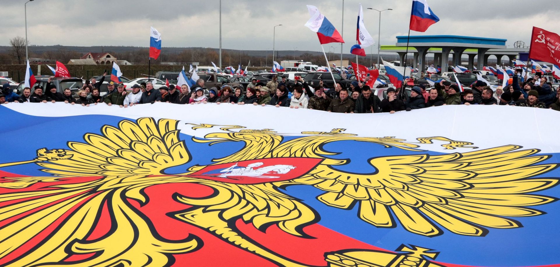 Personas en un pueblo en las afueras de Simferopol, Crimea, sostienen una bandera rusa gigante durante una manifestación en apoyo de la guerra en curso de Rusia contra Ucrania el 5 de marzo de 2022. 