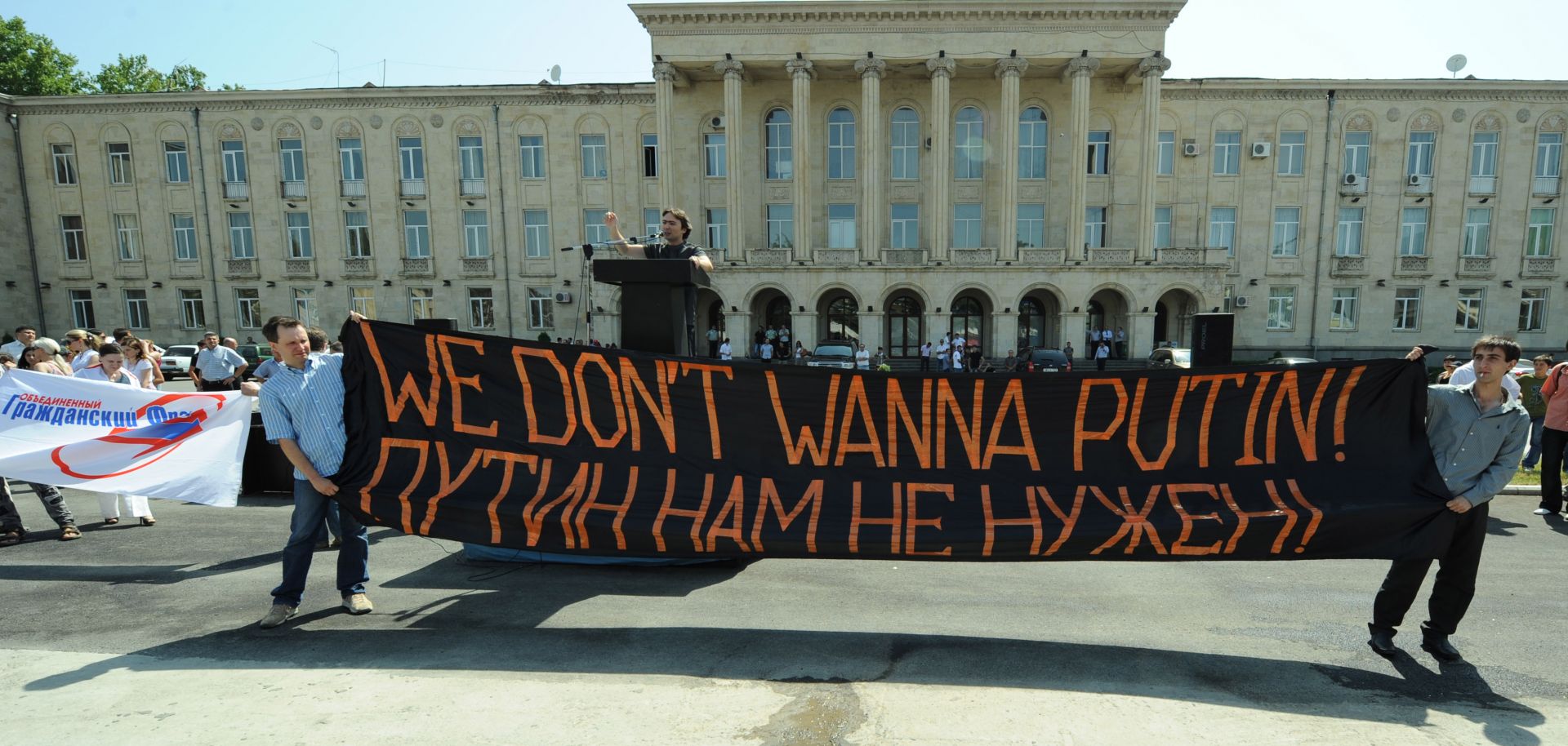 A Russian opposition activist gives a speech behind a large banner.